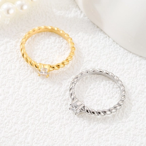 Detalle de anillos de acero de titanio trenzado con circonita cuadrada en oro y plata