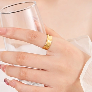 Wide gold titanium steel ring with BE THE CHANGE engraving shown on index finger