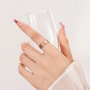 Rose gold stainless steel ring with BE THE CHANGE engraving worn by model holding glass