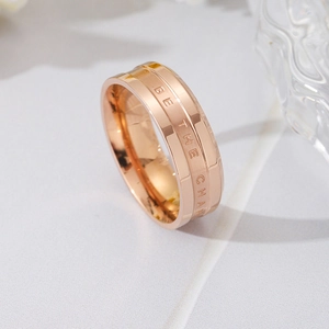 Detail of rose gold titanium ring featuring engraved 'BE THE CHANGE' text in central groove