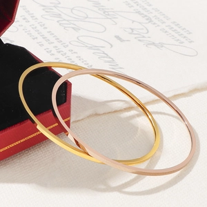 Polished 18K gold and rose gold titanium steel bangles on red jewelry gift box