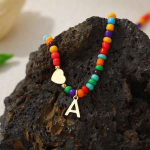 Detail of colorful beads with a gold heart pendant and letter A charm on dark rock