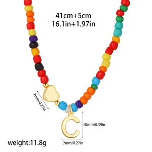 Detailed view of 14k gold heart and letter C pendant on rainbow beaded necklace