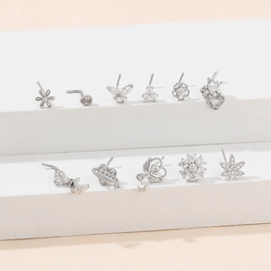 Macro shot of 11 assorted silver piercing studs featuring crystal flowers and butterflies