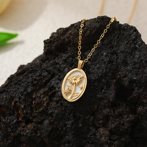 Détail du pendentif tournesol en or 18K sur nacre blanche avec une chaîne fine dorée
