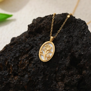 Détail du collier pendentif fleur en nacre gaufré or 18 carats sur pierre volcanique
