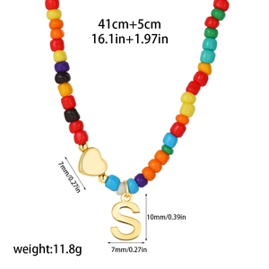 Detailed size view of colorful beaded letter S necklace with 14k gold heart pendant