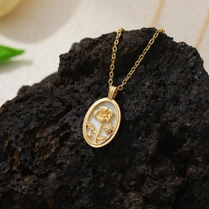 Gros plan du pendentif ovale en or 18K avec relief floral sur fond de pierre volcanique noire