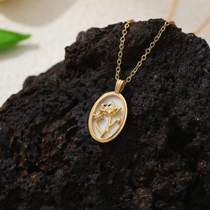 Détail du pendentif en nacre avec motif floral en or 18K et zircon sur une chaîne fine