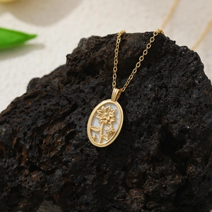 Détail d'un pendentif en nacre et or 18 carats avec motifs tournesol et étoile sur roche