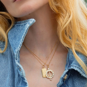 Detail of 18K gold-plated double-layer necklace with compass and quote pendant on model