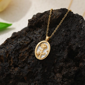 Détail d'un pendentif ovale plaqué or 18 carats avec rose en nacre sur pierre volcanique