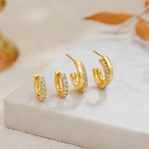 Μίνιμαλ επιχρυσωμένα σκουλαρίκια κρίκοι 18K με ζιργκόν σε φόντο από λευκό μάρμαρο