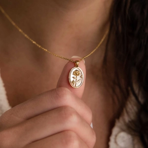 Gros plan du collier avec pendentif ovale fleuri en or 18 carats, nacre et pierre verte