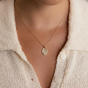 Détail du collier pendentif rose en nacre or 18K porté sur un cardigan en maille crème