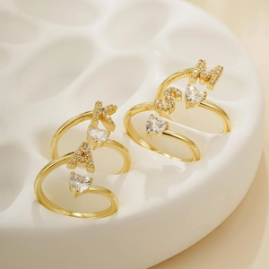Dettaglio di anelli regolabili placcati oro 18K con cuore in cristallo e lettere
