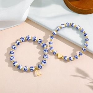 Detail of blue and white ceramic floral beads with gold heart and letter L charms