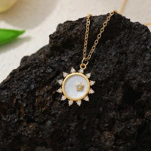 Macro shot of gold compass necklace with mother of pearl inlay and sparkling zircon stones