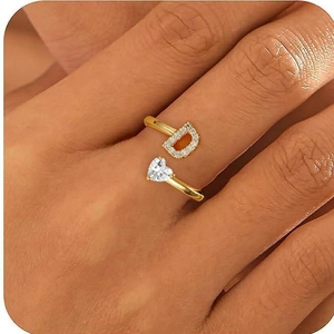 Dettaglio anello in oro 18K con lettera D e zircone a cuore sul dito da donna