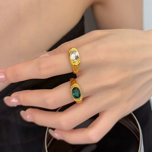 Macro detail of 18K gold-plated vintage ring set with oval emerald and clear zircon gems