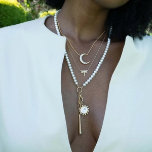 Detail of layered 18K gold plated necklaces with pearl and sun pendant on a model