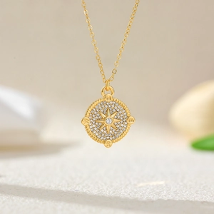 Macro detail of 18K gold compass pendant necklace with shimmering zircon and star motif