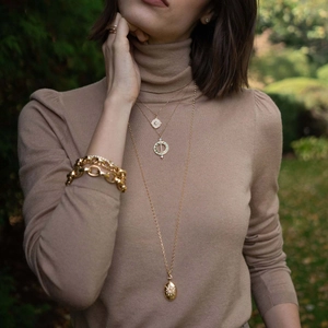 Detailed layered 18K gold necklaces with compass pendant and starburst charms on model