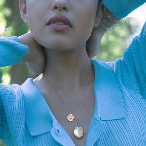 Detail of 18K gold plated double pendant necklace with star coin and oval locket
