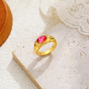 Detail of 18K gold ring featuring a large oval pink gemstone on textured stone surface