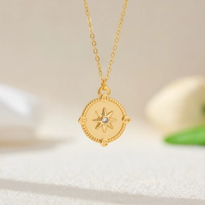 Macro detail of 18K gold plated compass pendant necklace with sparkling center zircon