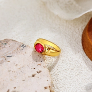 Macro shot of 18K gold ring featuring an oval ruby gemstone on a natural stone base