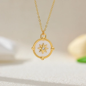 Close-up of 18K gold-plated compass pendant with zircon inlay and white enamel detail