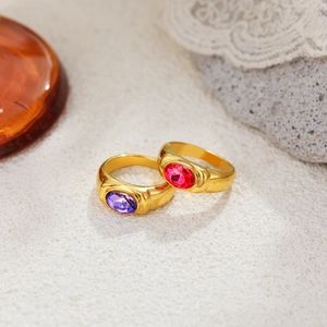 Vintage 18K gold plated rings with purple and red oval gemstones on a white textured surface