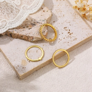 Close-up of three 18K gold-plated minimalist rings with zircon on marble texture