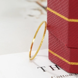 Minimalist matte gold titanium steel thin ring displayed on a red jewelry box background