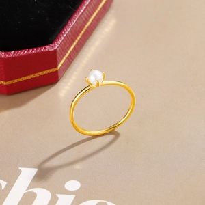 Detail eines eleganten Goldrings mit Perle in Vier-Krallen-Fassung auf roter Schmuckschatulle