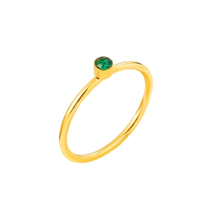 Detail of minimalist gold ring with bezel-set green round zircon stone and polished finish