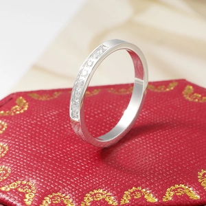 Macro detail of silver band with channel-set sparkling diamonds in a red jewelry box