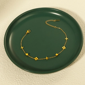 Eleganter goldener Titan-Fußkettchen mit Stern-, Klee- und Würfelanhängern in grüner Schale