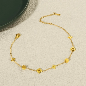 Detailansicht eines goldenen Titan-Fußkettchens mit Kleeblatt-, Stern- und Würfelanhängern