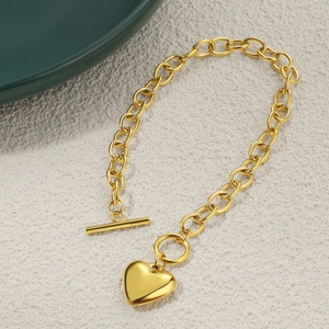 Detail of gold chunky chain bracelet with heart pendant and trendy OT toggle clasp