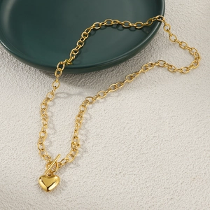 Detailed shot of golden heart pendant necklace with toggle clasp on green ceramic plate
