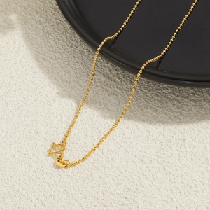 Close-up of 24K gold-plated beaded chain with W-clasp on a modern black and white backdrop