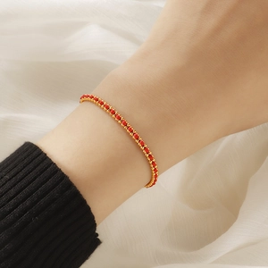 Elegant woven red rope bracelet with gold titanium steel beads worn on a wrist