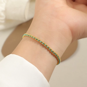 Close-up of a gold-plated bracelet with blue gemstones on a female model's wrist