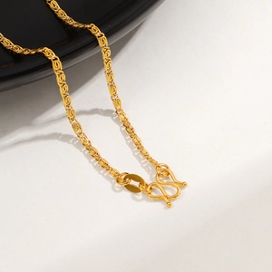 Detailed macro view of 24K gold plated twist chain necklace with secure M-shaped clasp