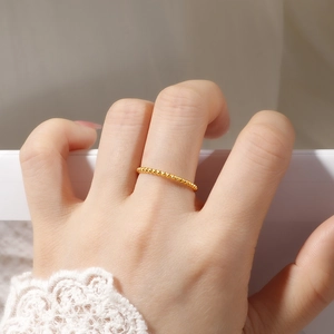 Close-up of a slim 18K gold-plated beaded ring worn by a model in soft lighting