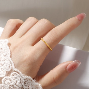 Close-up of minimalist beaded 18K gold plated titanium steel ring on finger