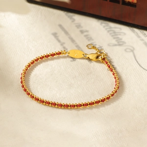 Detailed view of red woven rope bracelet with gold beads and engraved letter K tag