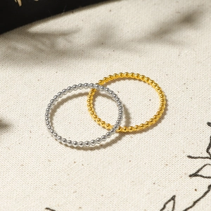 Minimalist 18K gold and silver beaded stackable rings on natural fabric background